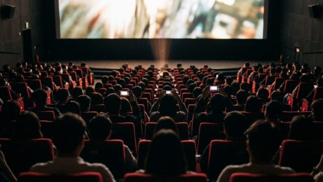 A packed Seoul movie theater audience faces the glowing screen on premiere night