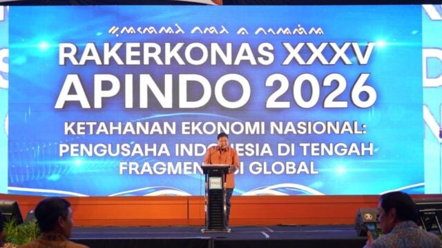 Menteri Koordinator Perekonomian memberikan pidato dalam forum APINDO di Makassar, latar belakang peta Indonesia dan grafik